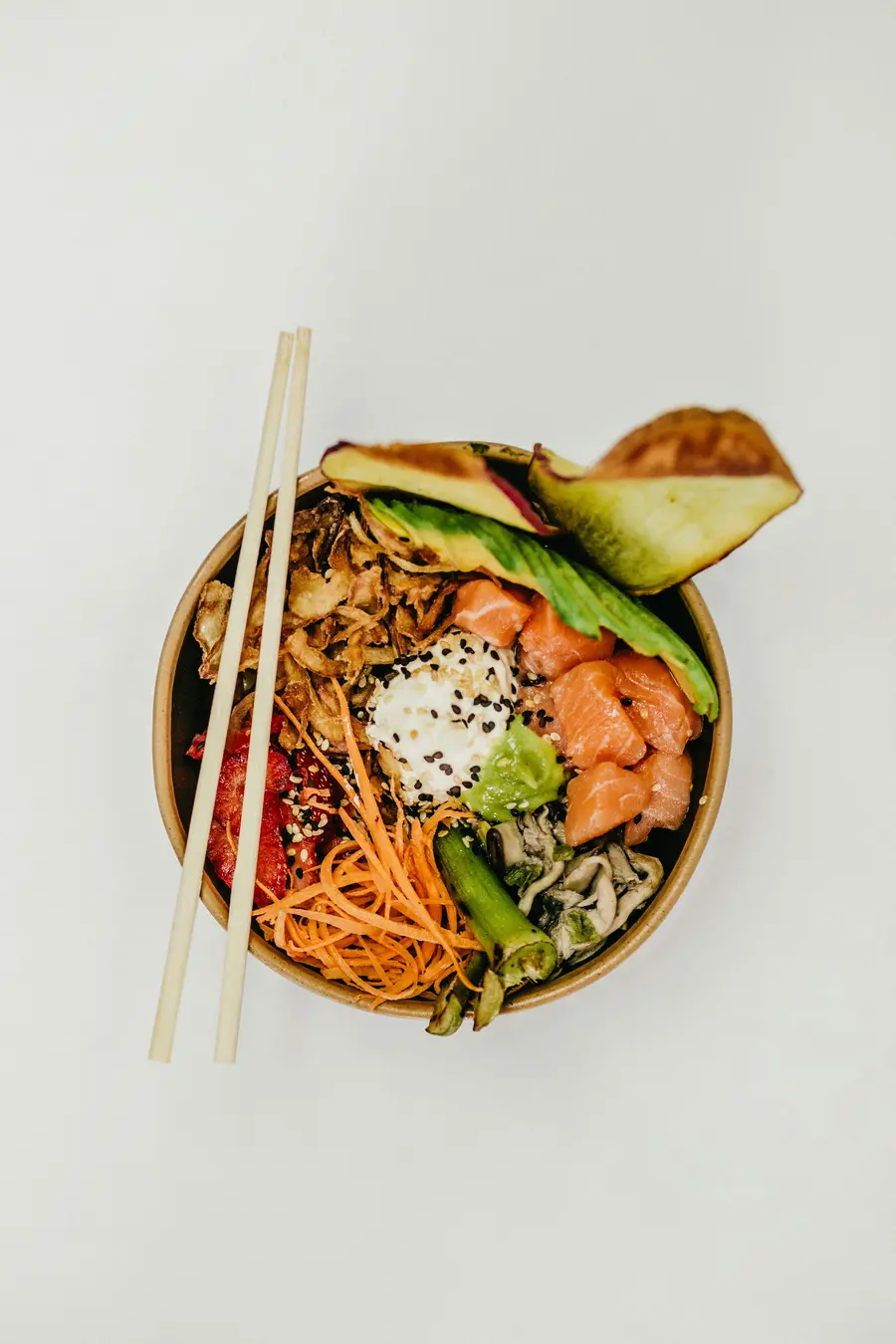 A prepared poke bowl photographed from above with chopsticks