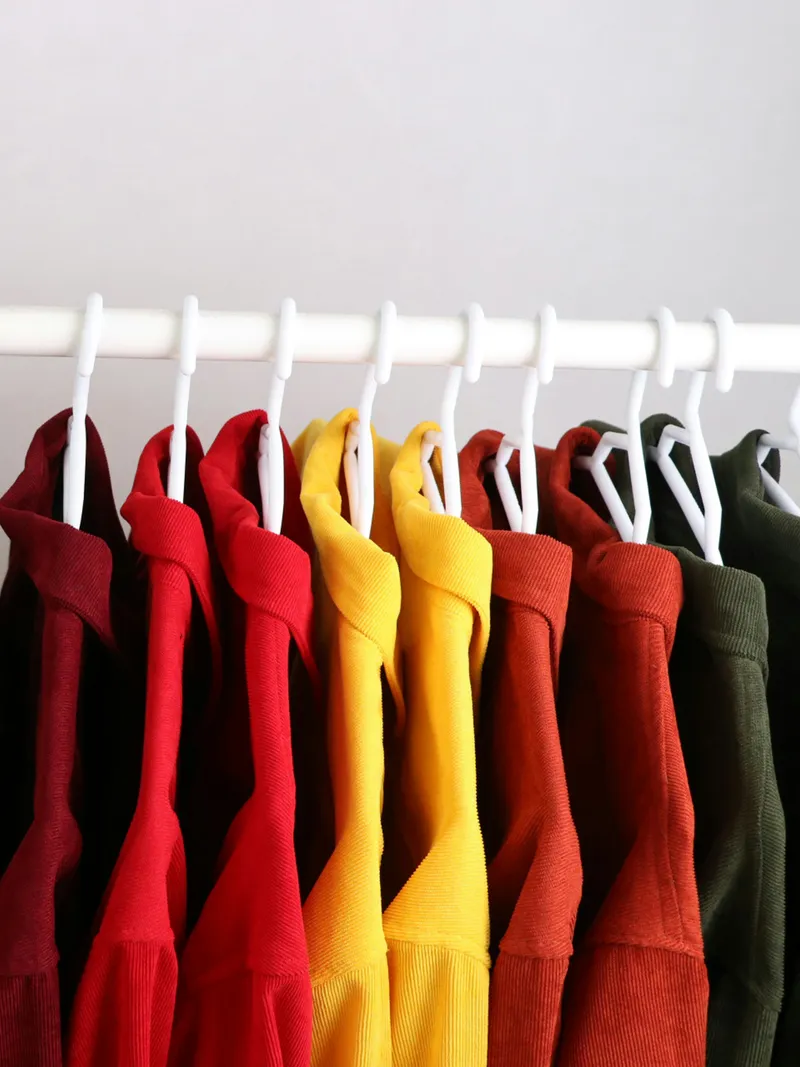 Rack of colourful corduroy shirts on hangers in a retail store, where fashion assortments reach shoppers and carbon and nature impact is reported